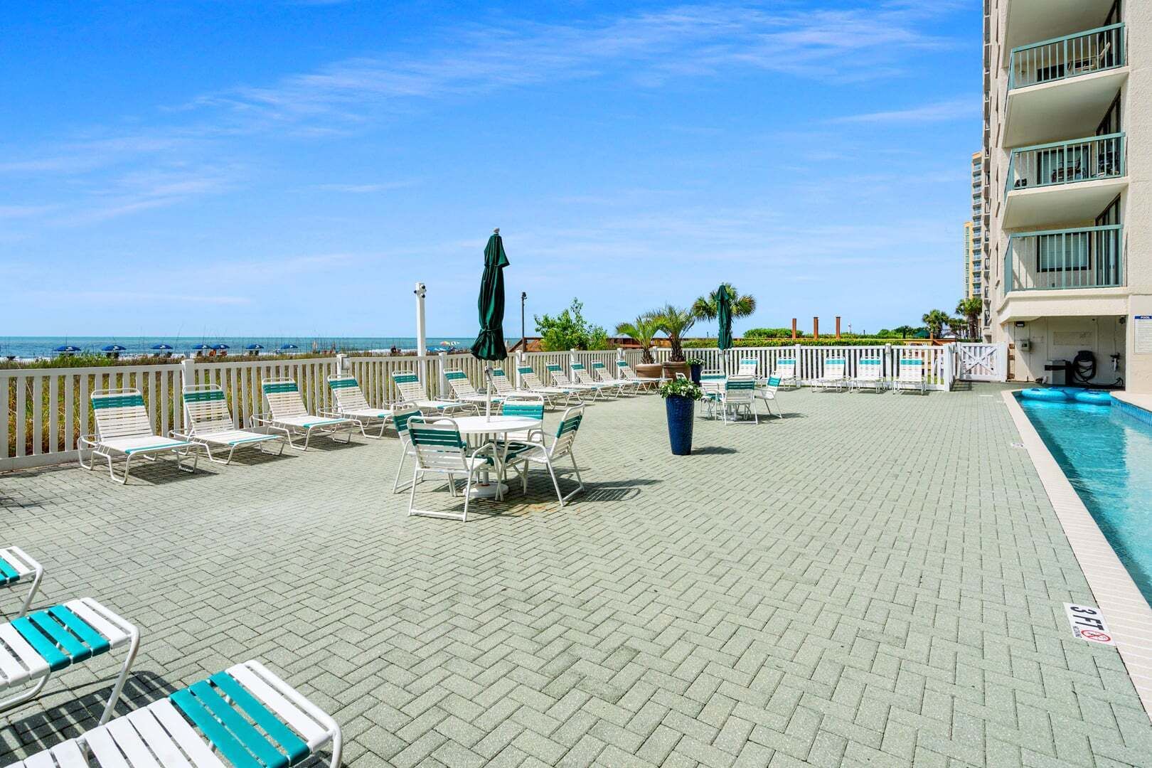 Ein Poolbereich auf dem Dach mit Liegestühlen und Sonnenschirmen, einem Pool und Blick auf den Ozean.
