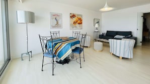 A modern living room with a dining area, featuring a sofa, a coffee table, and a dining table with chairs.