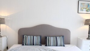 A neatly made bed with striped pillows, a grey headboard, and two bedside lamps.
