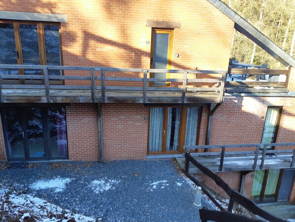 A two-story building with a wooden balcony, brick walls, and numbered windows.