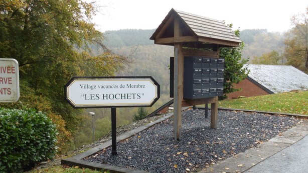 A sign for 'Village vacances de Membre "LES HOCHETS"' with a wooden structure and mailbox.