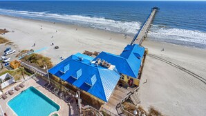 Ein Strandhotel mit Pool, direktem Strandzugang und einer Pier, die sich ins Meer erstreckt.