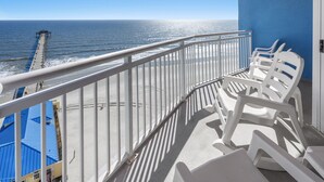 Ein Balkon mit weißen Plastikstühlen, Blick auf das Meer und ein Pier in der Ferne.