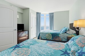 Une chambre d’hôtel avec un lit, une commode, une télévision et une fenêtre avec des rideaux.