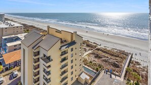 Een hoog hotel met uitzicht op een strand en een helder zicht op de oceaan.