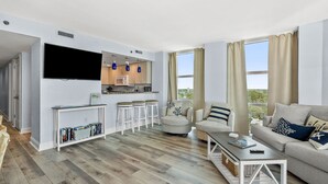 Een moderne woonkamer met een flatscreen televisie, een keukenhoek en een eethoek.