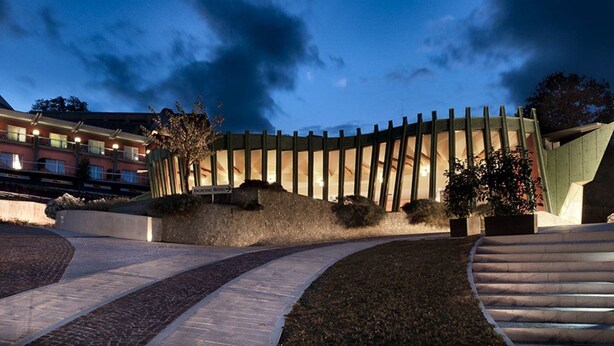 A hotel with a curved exterior wall, a landscaped area with a pathway, and a staircase leading to the entrance. - Bouganville Hill Resort Wellness Space (Picerno)