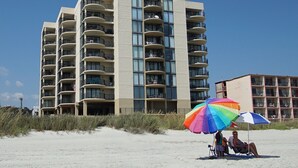 Ein mehrstöckiges Hotel mit Balkonen und großen Fenstern in Strandnähe.