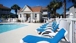 A pool area with lounge chairs and a small building with a white fence. - Condo in quiet resort w/amazing pool & Jacuzzi, great privte deck - 1 block from the beach (North Myrtle Beach)