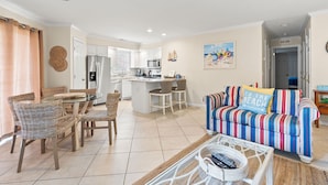 A modern kitchen with white cabinets, stainless steel appliances, and a dining area with wicker chairs and a glass table. - Condo in quiet resort w/amazing pool & Jacuzzi, great privte deck - 1 block from the beach (North Myrtle Beach)