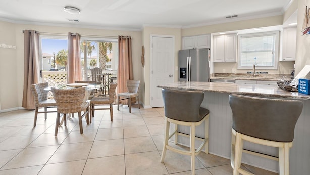 A modern kitchen with a marble countertop, stainless steel appliances, and a dining area with wicker chairs. - Condo in quiet resort w/amazing pool & Jacuzzi, great privte deck - 1 block from the beach (North Myrtle Beach)
