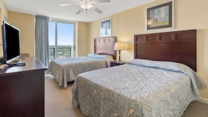 A hotel room with two beds, a desk with a TV, a ceiling fan, and a window with a view. - Penthouse condo w/ stunning ocean views, pools, lazy river, and on-site cafe (Family-Friendly!) (North Myrtle Beach)
