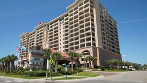 A large, multi-story hotel with a central courtyard, palm trees, and a sign for a golf course. - Penthouse condo w/ stunning ocean views, pools, lazy river, and on-site cafe (Family-Friendly!) (North Myrtle Beach)
