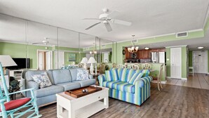 Un salón amplio con un sofá azul, una mesa de centro blanca y un sillón mecededor.