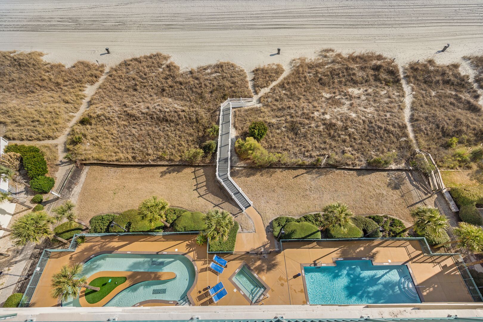 An aerial view of a resort with a beach, a pool area, and a bridge connecting different sections.