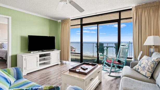 Una habitación de hotel con balcón, televisión, sofá y mesa de centro.