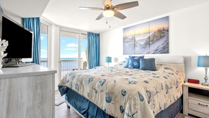 A bedroom with a large bed, a ceiling fan, a TV, and a view of the ocean. - Beach condo with outdoor features, pools, lazy river, kids' pool (North Myrtle Beach)