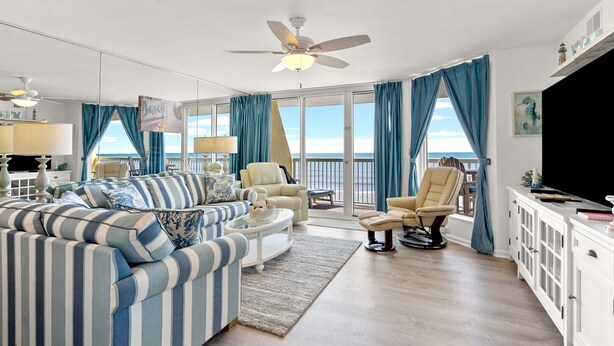 A spacious living room with a large sofa, armchairs, and a television. - Beach condo with outdoor features, pools, lazy river, kids' pool (North Myrtle Beach)
