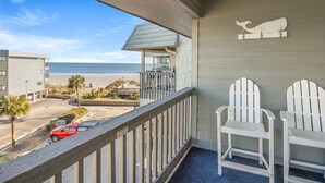 A balcony with a view of the beach, two white Adirondack chairs, and a whale-shaped wall decoration. - Family & fishermen-friendly condos at quiet resort with pool and pier (North Myrtle Beach)