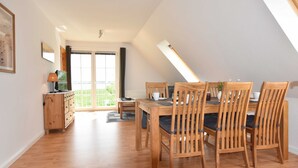 Un coin repas avec une table et des chaises en bois, une lampe et une vue sur l’extérieur.