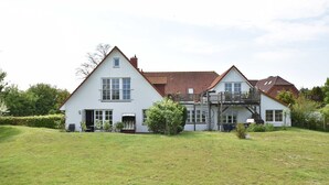 A two-story house with a large front lawn, a balcony, and a staircase leading to the upper floor. - App.7 / 3-room (5 adults + 1 infant), ground floor - Ferienwohnungen Zum Breitling OVS 691 (Insel Poel)