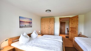 A bedroom with a wooden bed, a nightstand, a bedside lamp, a wooden wardrobe, and a painting on the wall. - App.7 / 3-room (5 adults + 1 infant), ground floor - Ferienwohnungen Zum Breitling OVS 691 (Insel Poel)