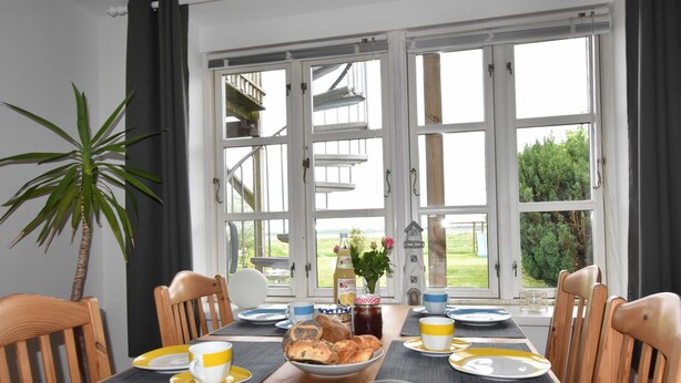 A dining table with chairs, plates, cups, and a bowl of food. - App.7 / 3-room (5 adults + 1 infant), ground floor - Ferienwohnungen Zum Breitling OVS 691 (Insel Poel)