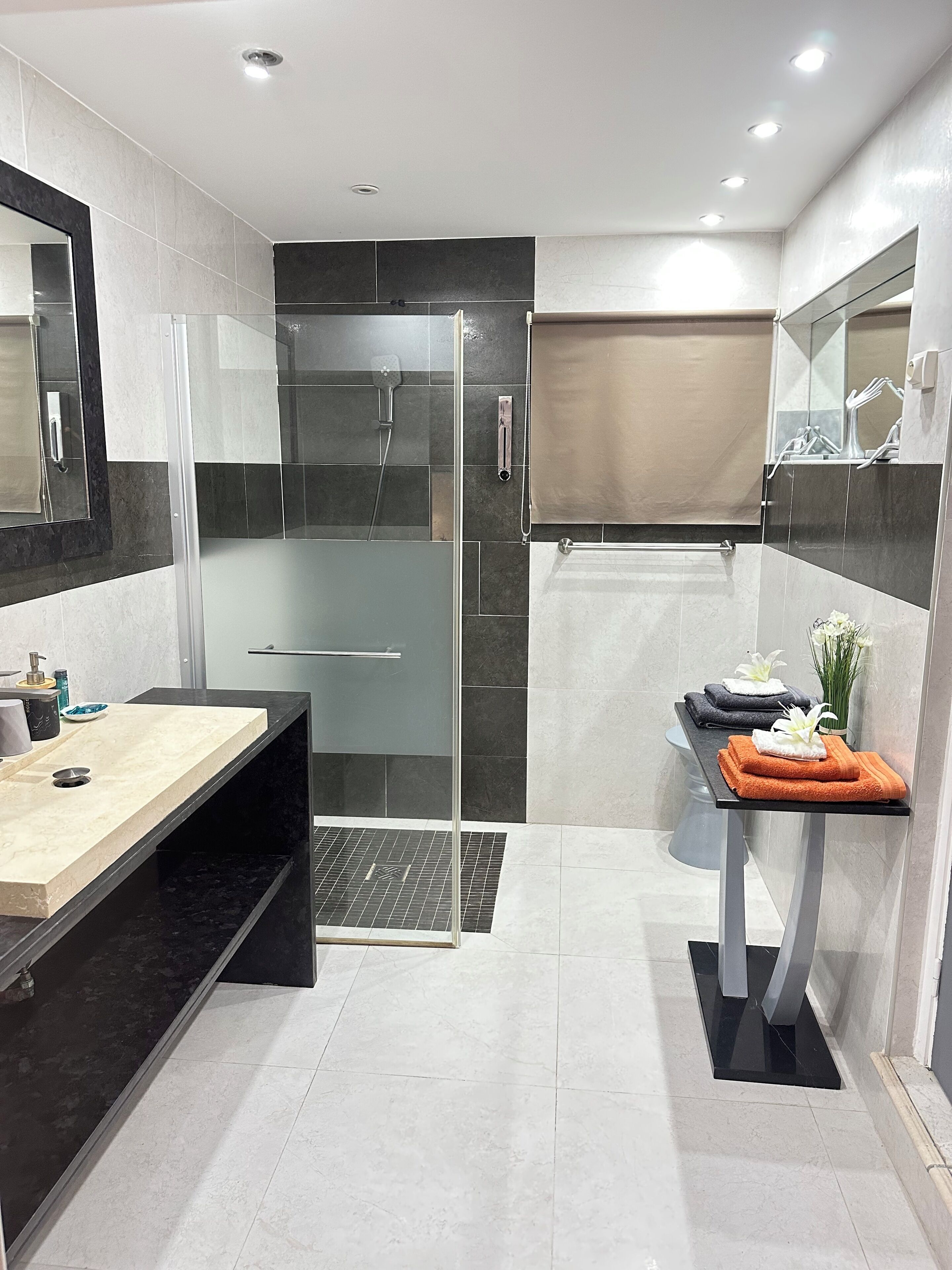 Un bagno moderno con doccia vetrata, lavabo e porta asciugamani con asciugni piegati.