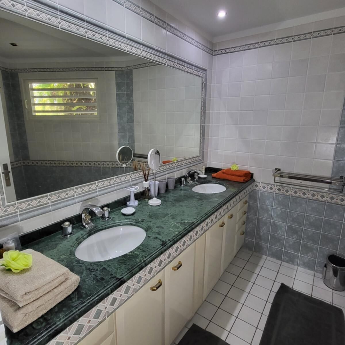 Une salle de bain avec deux lavabos, un grand miroir et un porte-serviettes.