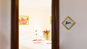 A hotel room with a bed, a nightstand, a lamp, and a floral arrangement.