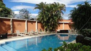 A swimming pool with lounge chairs and palm trees. - Hotel Suites Merlyn Airport (San Juan)