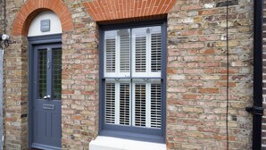 A brick building with a grey door and a window with shutters. - Crab Cottage (Whitstable)