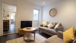 A living room with a sofa, a TV, and a small table. - Crab Cottage (Whitstable)