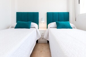 Habitación doble con dos camas, cada una con cabecero verde aguamarina y ropa de cama blanca.