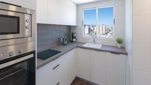Eine kompakte Küche mit Einbauofen, Spüle und Fenster mit Blick auf die Stadt.