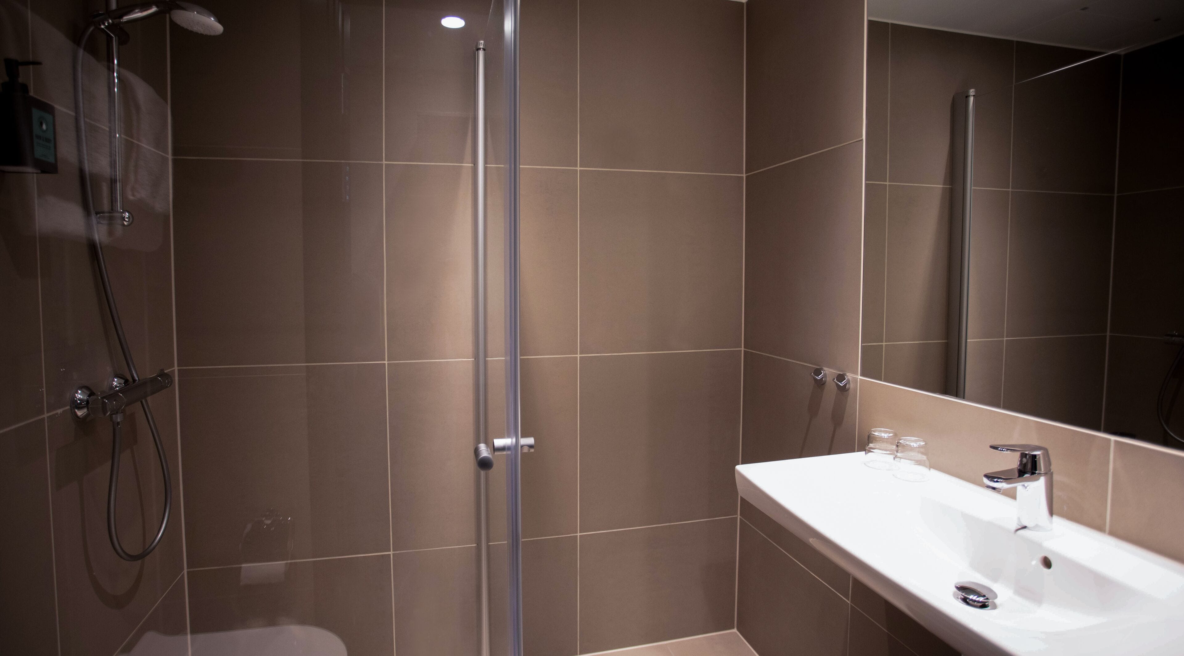 Un baño moderno con ducha, lavamanos y espejo.