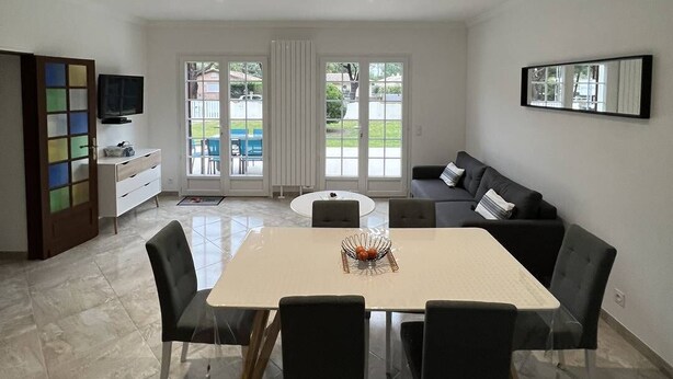 Una sala de estar moderna con comedor, ventanas amplias y vistas al exterior.