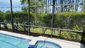 A swimming pool with a hot tub, surrounded by a metal fence and lush greenery. - Villa Hideaway with pool and gamesroom (Davenport)