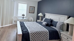 A bedroom with a bed, two bedside tables, a ceiling fan, a window with blinds, and a chair. - Villa Hideaway with pool and gamesroom (Davenport)