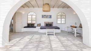Ein Zimmer mit einer weißen, gewölbten Decke, einem gewobenen Korb, einer Bank und einem Tisch mit einer Obstschale.