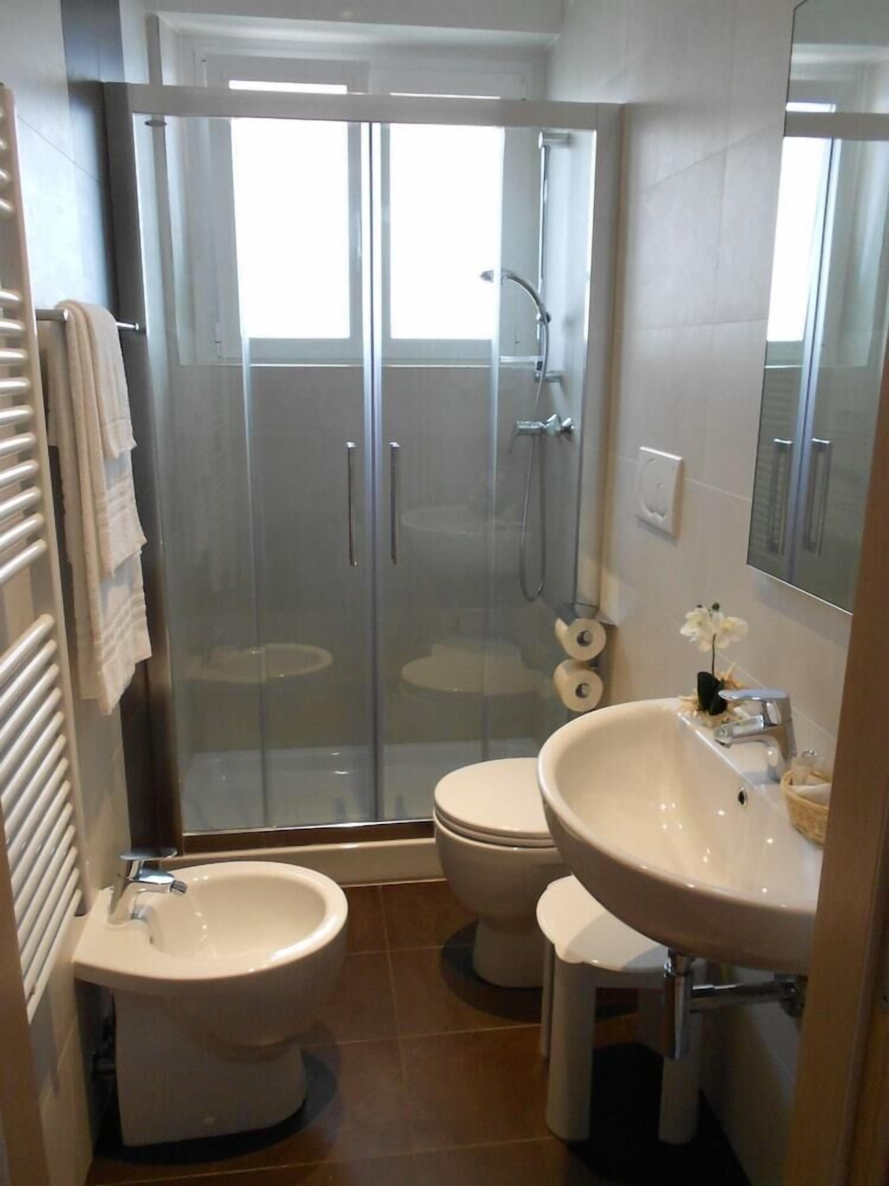 A bathroom with a glass-enclosed shower, a bidet, a toilet, and a sink.