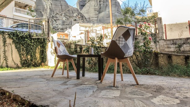 Een terras met een tafel en stoelen, omgeven door een stenen muur en begroeiing.
