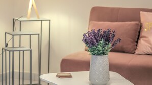 Een moderne woonkamer met een witte tafel, een vaas met bloemen, een bank met kussens en een lamp.