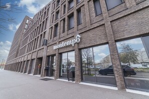 Ein modernes Gebäude mit einem gut sichtbaren 'montempo'-Schild, großen Fenstern und einer Ziegel-Fassade.
