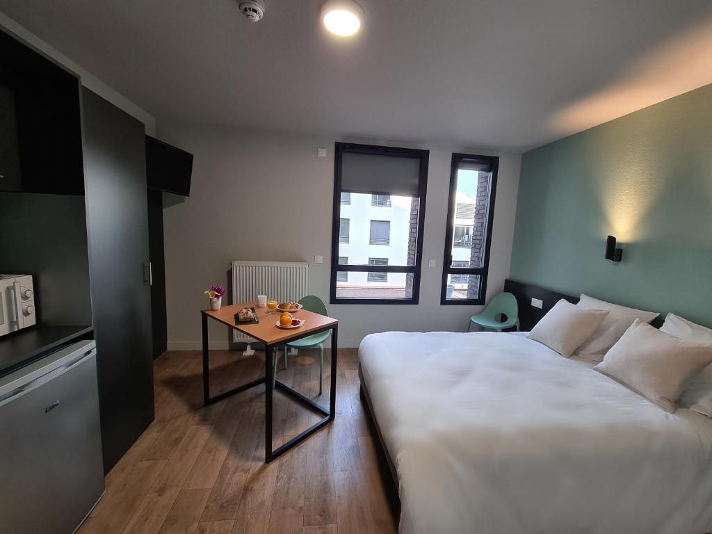Habitación de hotel con cama, una mesa con provisiones para el desayuno, un radiador y una ventana.
