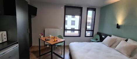 Habitación de hotel con cama, una mesa con provisiones para el desayuno, un radiador y una ventana.