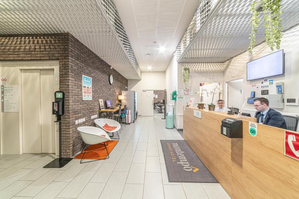 A hotel reception area with a reception desk, seating area, and a brick wall.