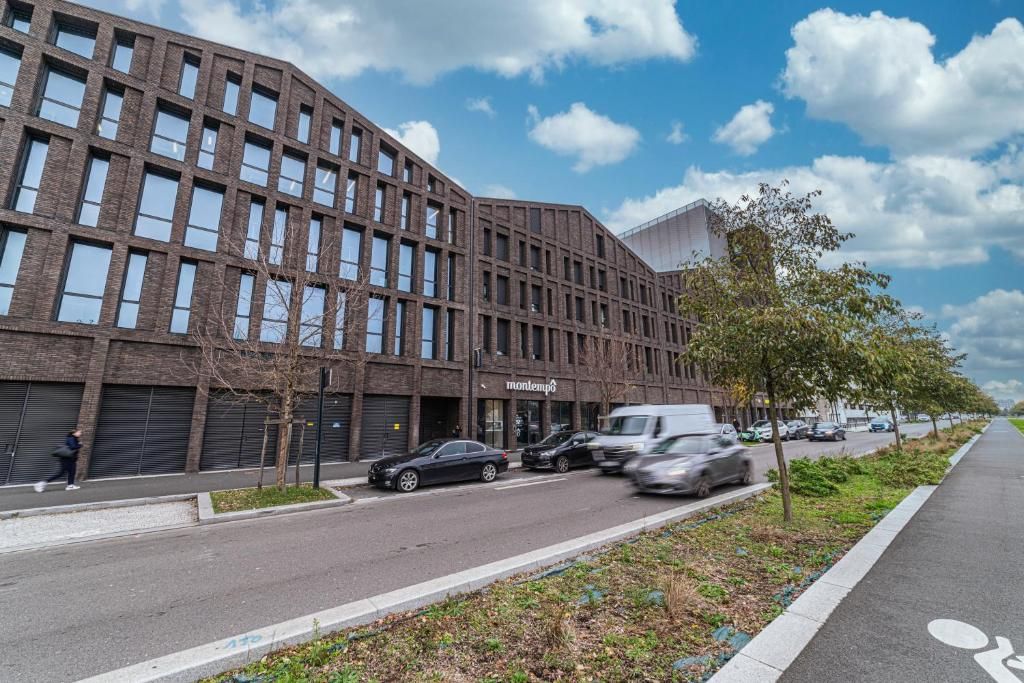 A modern building with a brick facade, a bike lane, and parked cars.