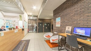 A reception area with a wooden desk, two white chairs, a computer, and a sign indicating WiFi availability. - Montempô Bordeaux centre - Bassins à flot (Bordeaux)