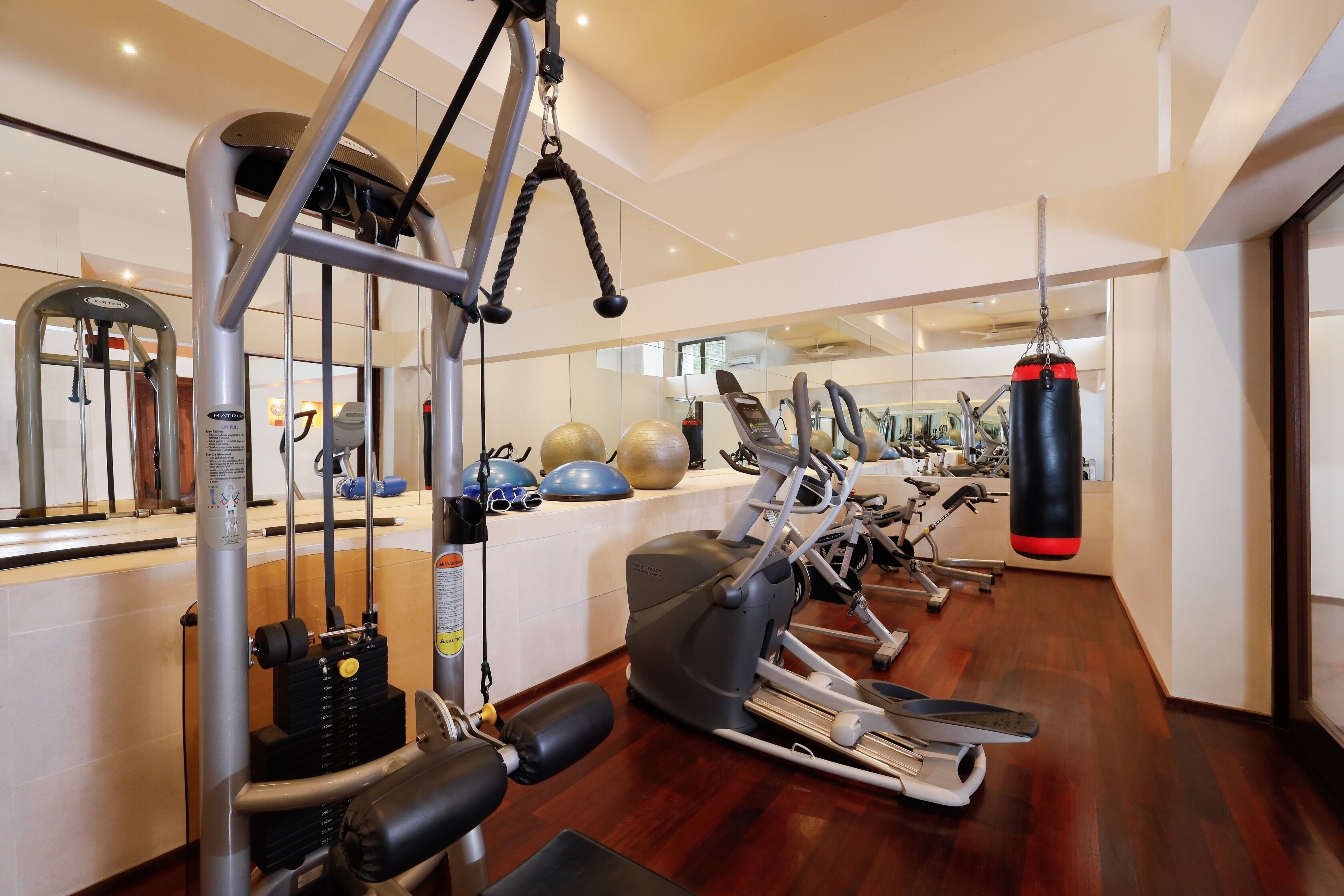 A modern gym with various exercise equipment, including treadmills, a punching bag, and weight machines.